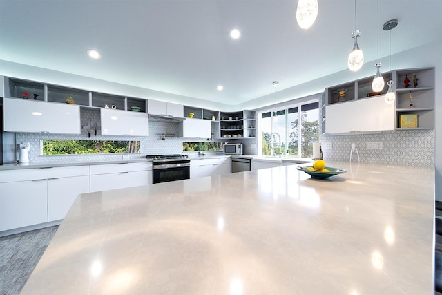 kitchen featuring white cabinets, stainless steel appliances, light countertops, open shelves, and backsplash