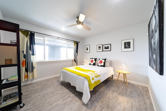 bedroom with a ceiling fan, baseboards, and wood finished floors