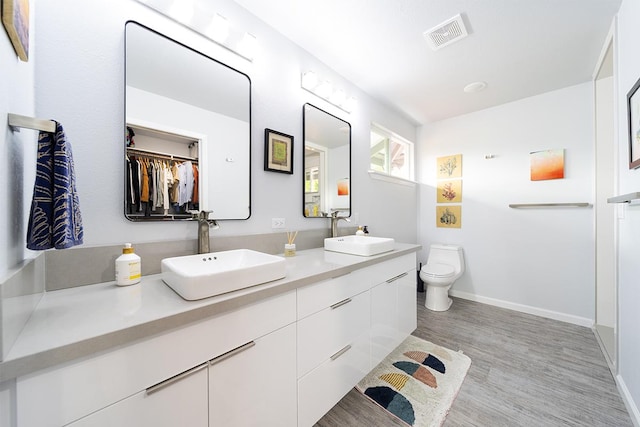 bathroom with visible vents, a sink, toilet, and wood finished floors