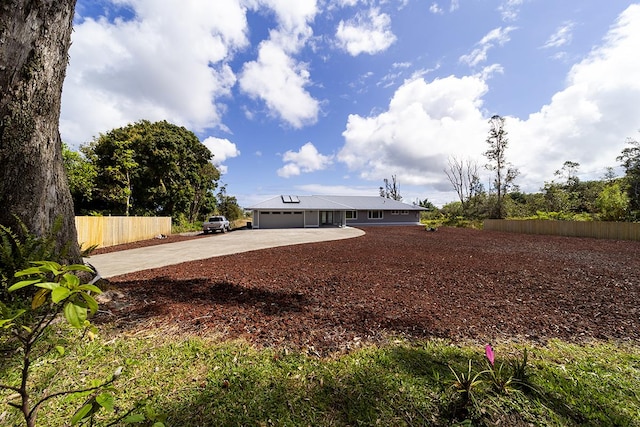 view of yard featuring driveway, an attached garage, and fence