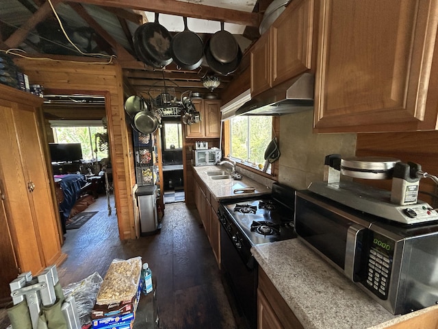 kitchen featuring black range with gas stovetop, a wealth of natural light, sink, and wall chimney range hood