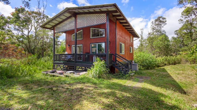 rear view of house featuring a deck and a lawn