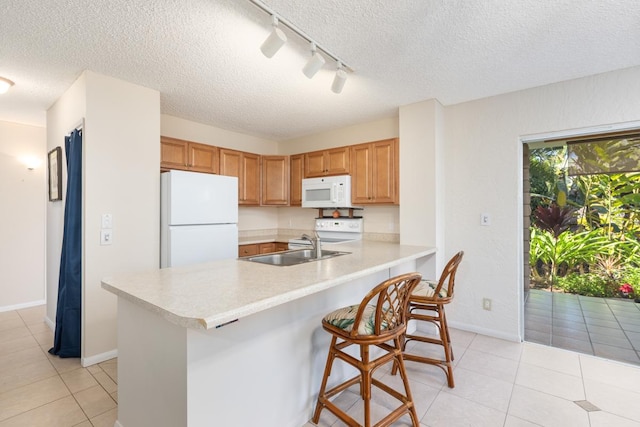 kitchen with light tile patterned flooring, sink, a kitchen breakfast bar, kitchen peninsula, and white appliances