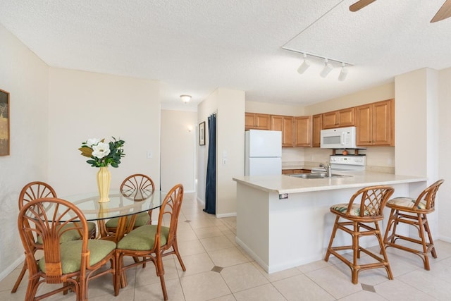 kitchen featuring sink, a breakfast bar area, white appliances, kitchen peninsula, and ceiling fan