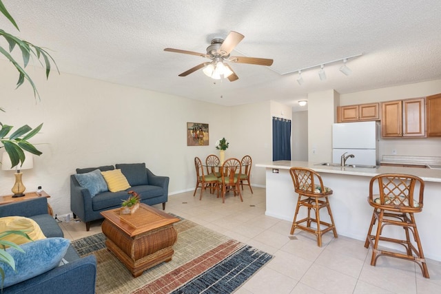 living room with ceiling fan, sink, a textured ceiling, and light tile patterned flooring