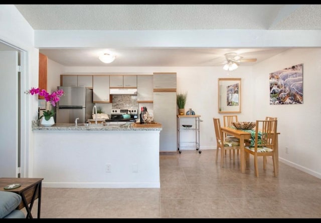 kitchen with a ceiling fan, under cabinet range hood, appliances with stainless steel finishes, a peninsula, and decorative backsplash