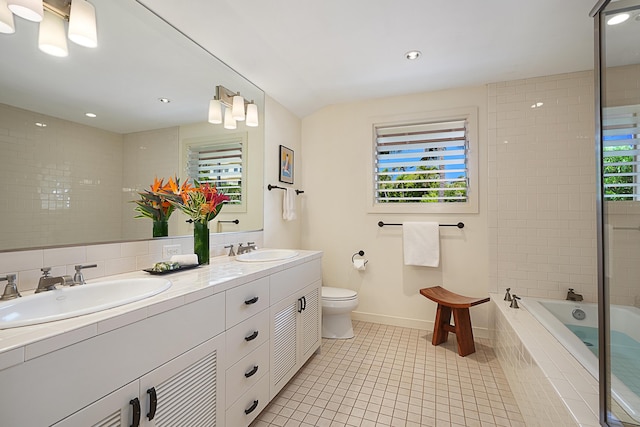 bathroom featuring a relaxing tiled tub, tile patterned floors, toilet, and vanity