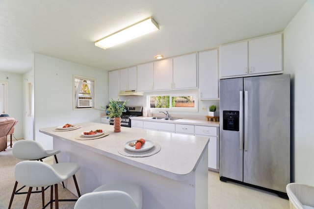 kitchen featuring under cabinet range hood, a breakfast bar area, stainless steel appliances, and light countertops