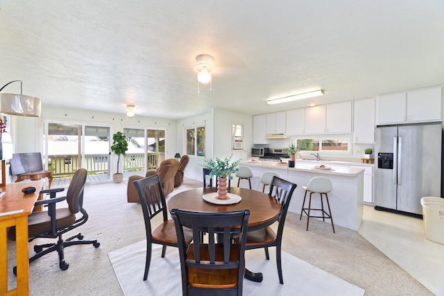 dining room with light carpet, plenty of natural light, and a textured ceiling