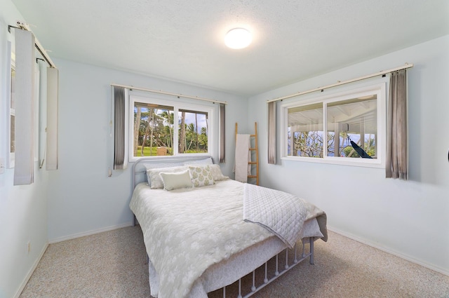 bedroom featuring carpet flooring, a textured ceiling, and baseboards