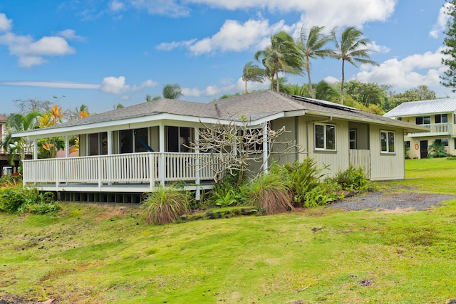 view of front of home featuring solar panels, a front yard, and a sunroom