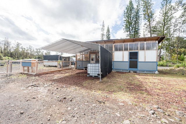 rear view of house featuring a carport and an outdoor structure