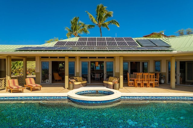 back of property with solar panels, metal roof, a patio area, and an outdoor pool