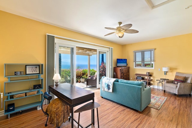 living area featuring ceiling fan, baseboards, and wood finished floors