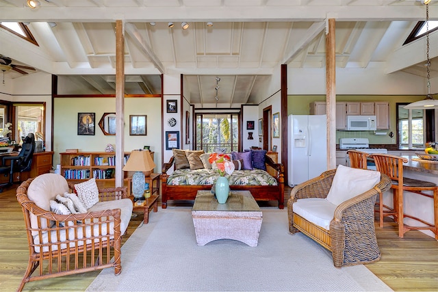 living room with lofted ceiling with beams, a wealth of natural light, and light wood-type flooring