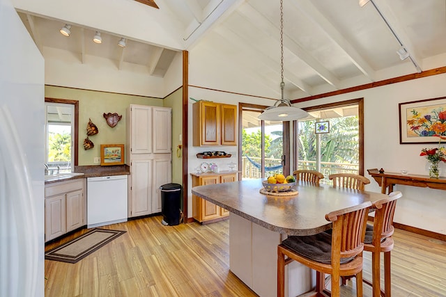 kitchen featuring a breakfast bar, decorative light fixtures, vaulted ceiling with beams, light hardwood / wood-style floors, and white appliances