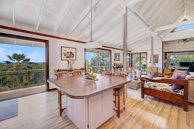 dining space with beamed ceiling, rail lighting, and light hardwood / wood-style flooring