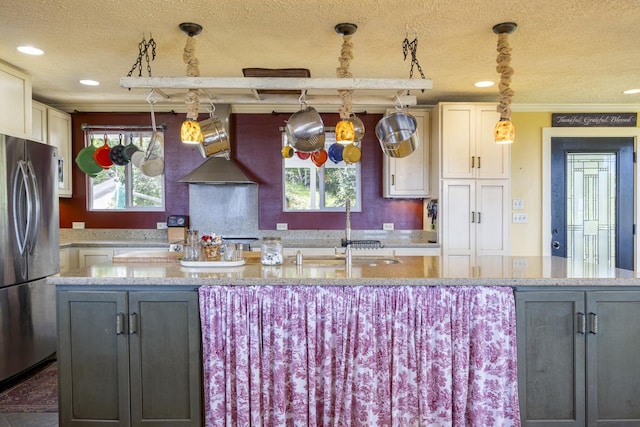 kitchen with stainless steel refrigerator, decorative light fixtures, sink, white cabinets, and light stone counters