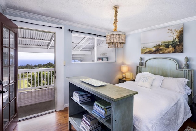 bedroom with ornamental molding, hardwood / wood-style floors, access to exterior, and a textured ceiling