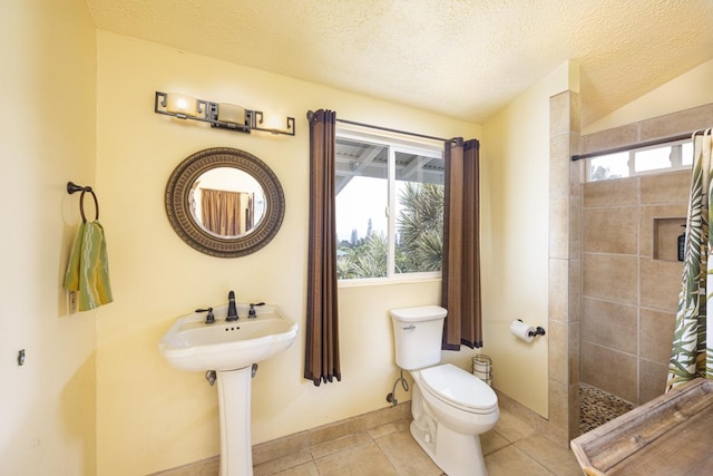 bathroom with tiled shower, tile patterned floors, toilet, and a textured ceiling