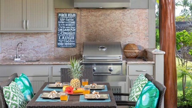 exterior space with stone counters, sink, exhaust hood, and decorative backsplash