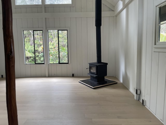 unfurnished living room featuring a wood stove and wood finished floors