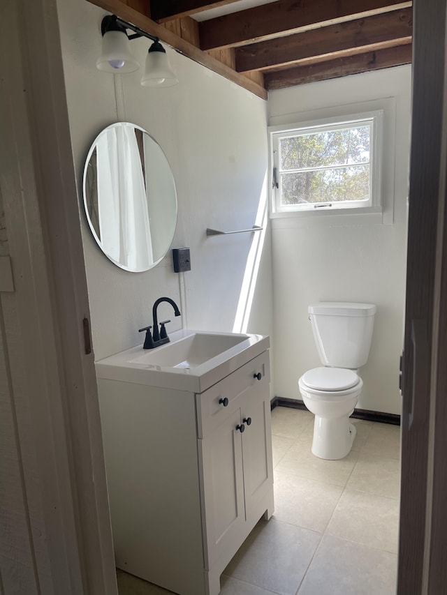 bathroom featuring toilet, vanity, baseboards, tile patterned floors, and beamed ceiling