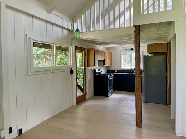 kitchen featuring brown cabinets, light wood finished floors, dark countertops, appliances with stainless steel finishes, and a sink