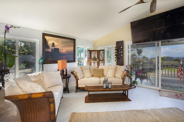 living room with ceiling fan, light hardwood / wood-style floors, and vaulted ceiling