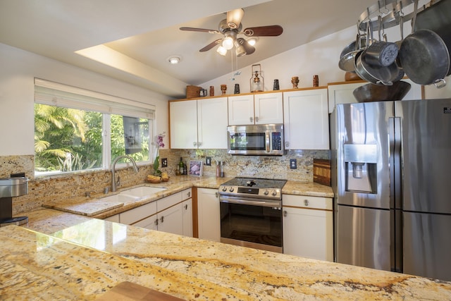 kitchen with sink, appliances with stainless steel finishes, white cabinetry, tasteful backsplash, and vaulted ceiling