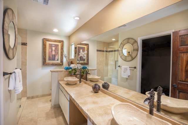 bathroom with a shower with door, vanity, and tile patterned floors