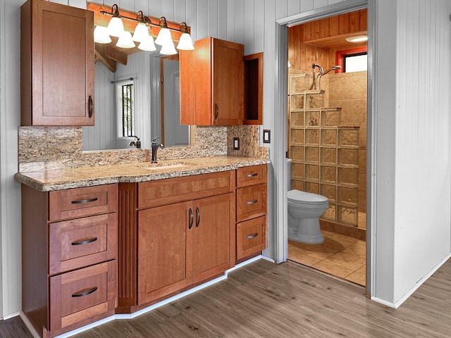 bathroom featuring hardwood / wood-style floors, backsplash, vanity, toilet, and walk in shower