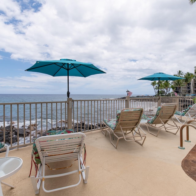 view of patio with a balcony, a water view, and a beach view