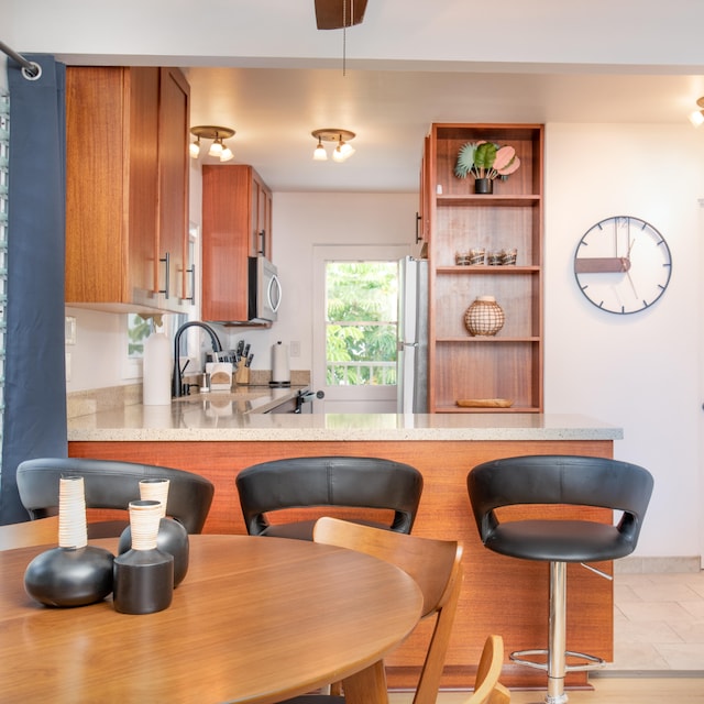 kitchen featuring stove, sink, kitchen peninsula, and refrigerator