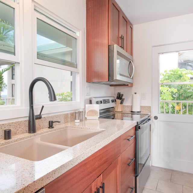 kitchen featuring light stone countertops, appliances with stainless steel finishes, sink, and light tile patterned floors