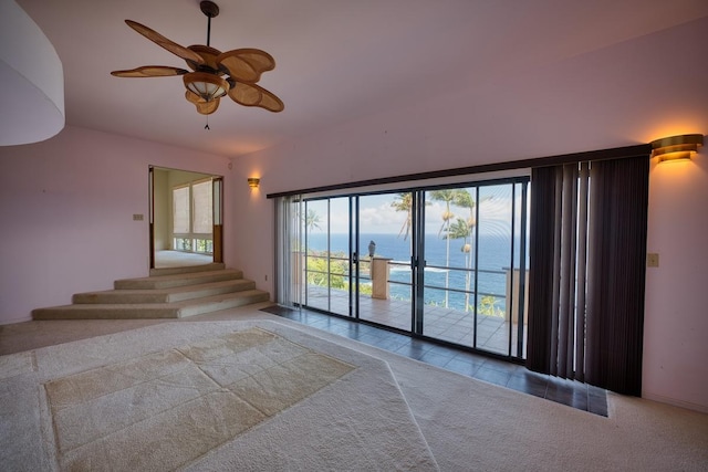 carpeted empty room with stairs and ceiling fan