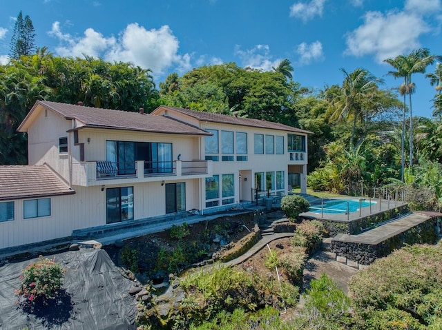 back of house featuring a balcony and an outdoor pool