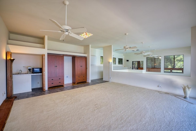 unfurnished living room featuring vaulted ceiling, ceiling fan, and dark colored carpet