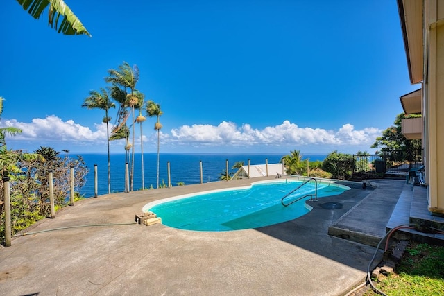 view of pool with a patio area, fence, and a water view