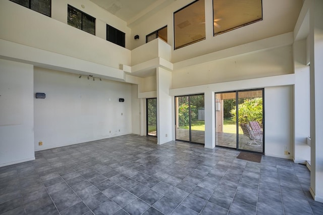 unfurnished room featuring baseboards and a towering ceiling