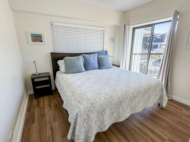 bedroom with dark wood-style floors, a textured ceiling, and baseboards