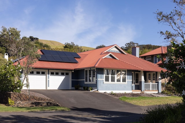 view of front of home featuring a garage, a porch, and solar panels