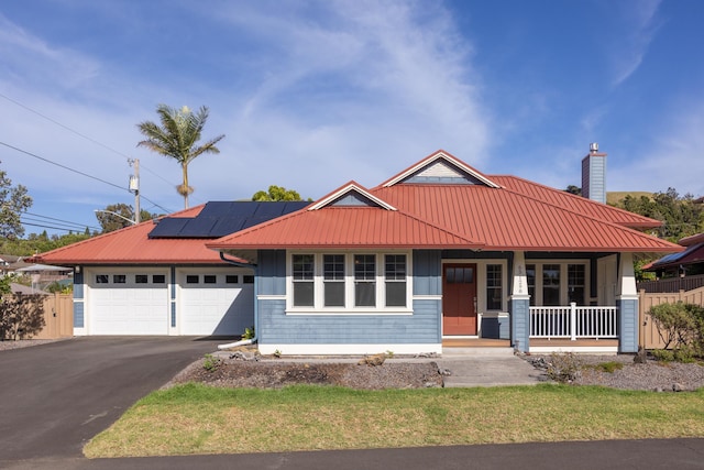 view of front of home featuring a porch, a garage, and solar panels