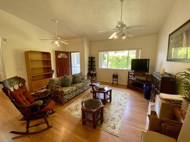 living room featuring vaulted ceiling, ceiling fan, a textured ceiling, and light hardwood / wood-style flooring