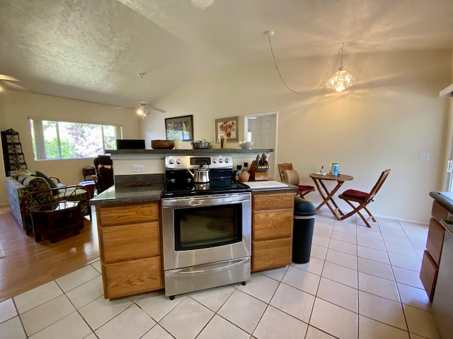 kitchen with light tile patterned floors, ceiling fan, a textured ceiling, stainless steel electric range oven, and vaulted ceiling