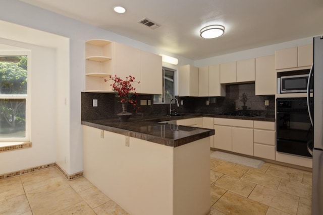 kitchen featuring kitchen peninsula, sink, backsplash, black appliances, and cream cabinetry