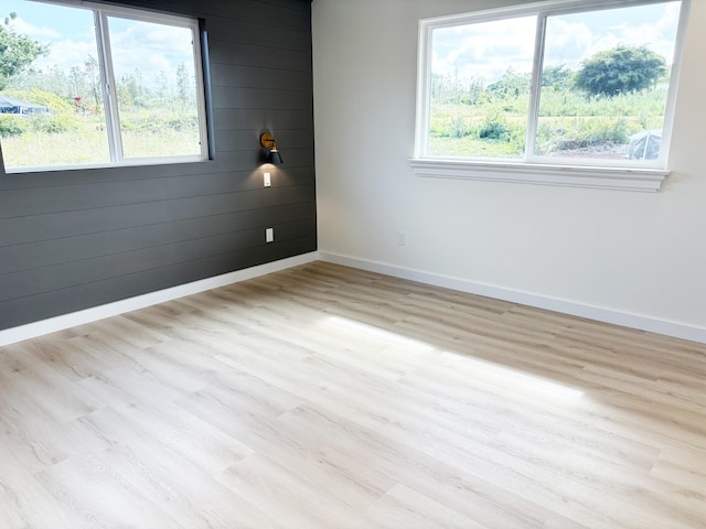 empty room with wooden walls and light wood-type flooring