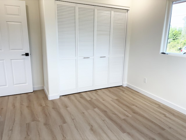 unfurnished bedroom with light hardwood / wood-style flooring and a closet