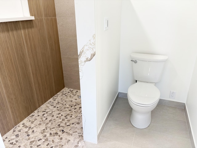 bathroom featuring tiled shower, toilet, and tile patterned flooring