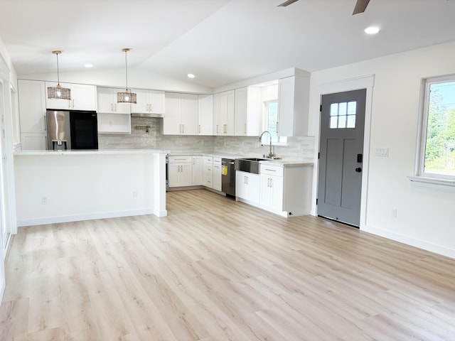 kitchen with appliances with stainless steel finishes, white cabinetry, lofted ceiling, sink, and backsplash